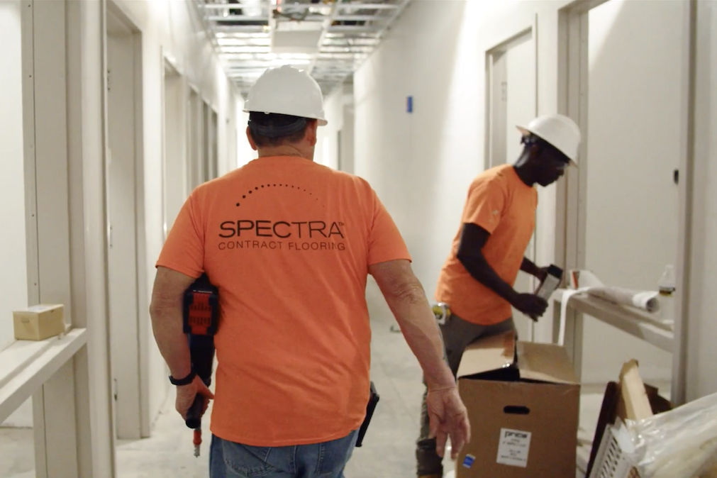 two men in orange spectra t-shirts on active job site