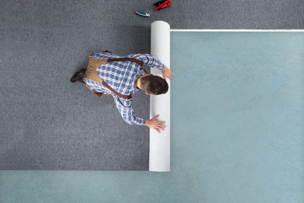 overhead image of man unrolling carpet flooring